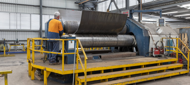 Steel experts using plate roller at the warehouse
